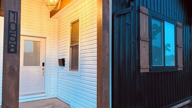 A wooden house with a covered porch, a front door, and a mailbox.