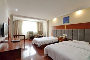 A hotel room with two beds, a desk, a TV, a chair, a window with curtains, and a painting on the wall.
