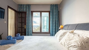 A hotel room with a bed, a window with curtains, a door, and a lamp on the bedside table. - Endless Blue Seafront Retreat - Mikra Mantineia (Paralia Vergas)