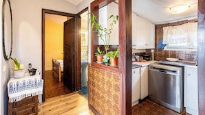 A kitchen with a dishwasher, wooden cabinets, and a potted plant. - Endless Blue Seafront Retreat - Mikra Mantineia (Paralia Vergas)