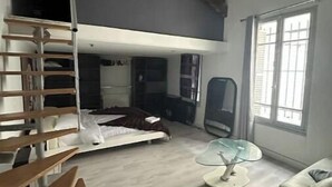 A spacious loft-style room with a loft bed, a glass table, a white sofa, and a staircase. - Loft Proche Centre Paris y Loger ou Professionnel (Suresnes)