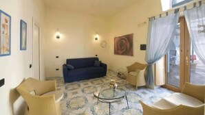 A living room with a sofa, chairs, a coffee table, and artwork on the walls. - TERRAZZA DI ROSA-SEA VIEW (Praiano)