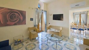 A living room with a large rose painting, a glass coffee table, and a sofa. - TERRAZZA DI ROSA-SEA VIEW (Praiano)