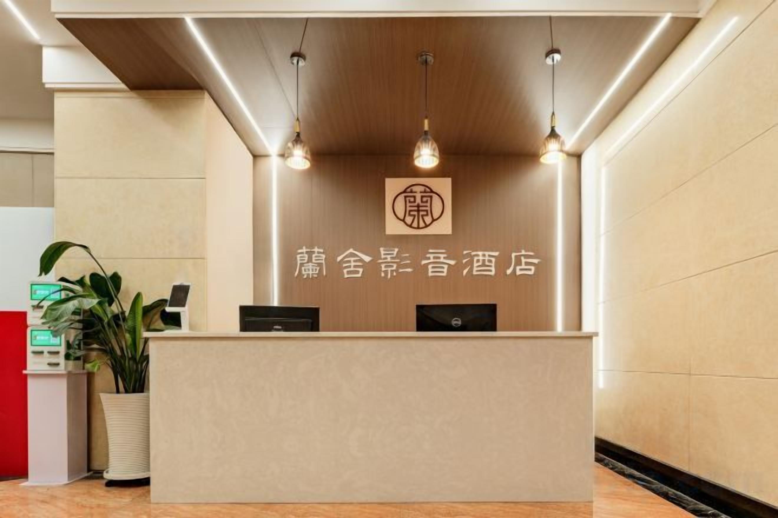A reception desk with a logo, a plant, and a red counter to the left.