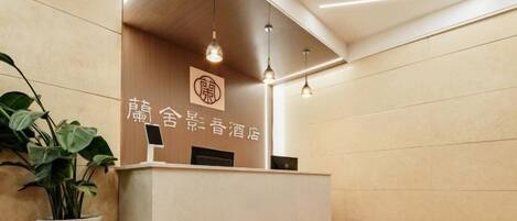 A reception desk with a modern design, featuring a logo and a potted plant.