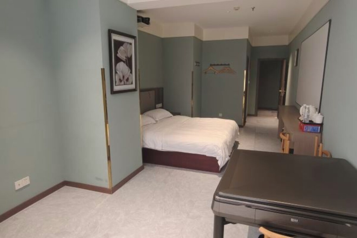 A hotel room with a bed, a desk, a mirror, and a framed picture on the wall.