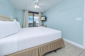 Ein Schlafzimmer mit Bett, Deckenventilator, Fernseher und einem Balkon mit Blick.