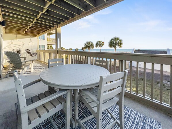 Relax in this serene beachside seating area with a round table and four chairs, offering a tranquil view of the ocean.