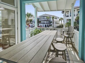 A wooden deck with a table and chairs, overlooking a residential area with multiple-story buildings and parked cars.