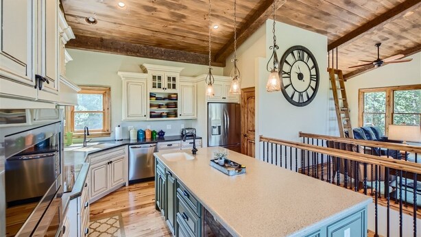 A spacious kitchen with a large island, wooden ceiling beams, and a clock on the wall. - Rocky Mountain Retreat 4 Bedroom Home by RedAwning (Black Hawk)