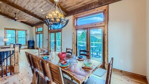 A dining area with a wooden table set for four, large windows, and a view of the outdoors. - Rocky Mountain Retreat 4 Bedroom Home by RedAwning (Black Hawk)