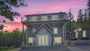 A two-story house with a stone facade, a balcony, and a gravel driveway. - Rocky Mountain Retreat 4 Bedroom Home by RedAwning (Black Hawk)