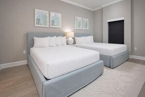 A bedroom with two beds, a nightstand, wall art, and a closed garage door. - Phoenix Gulf Towers 1607 3 Bedroom Condo by RedAwning (Orange Beach)