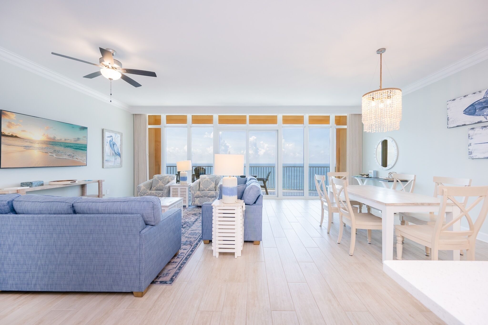 A spacious living room with a large sofa, a dining table, and a ceiling fan.