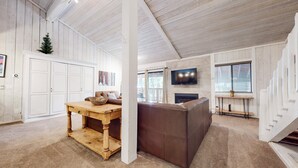 A spacious living room with a fireplace, a television, and a staircase.