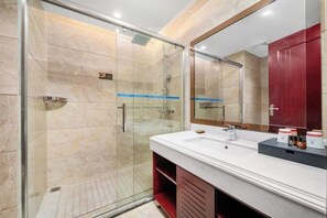 A modern bathroom with a glass-enclosed shower, a large mirror, and a white vanity with a red cabinet. - Xinlong Hotel (Wuhan)
