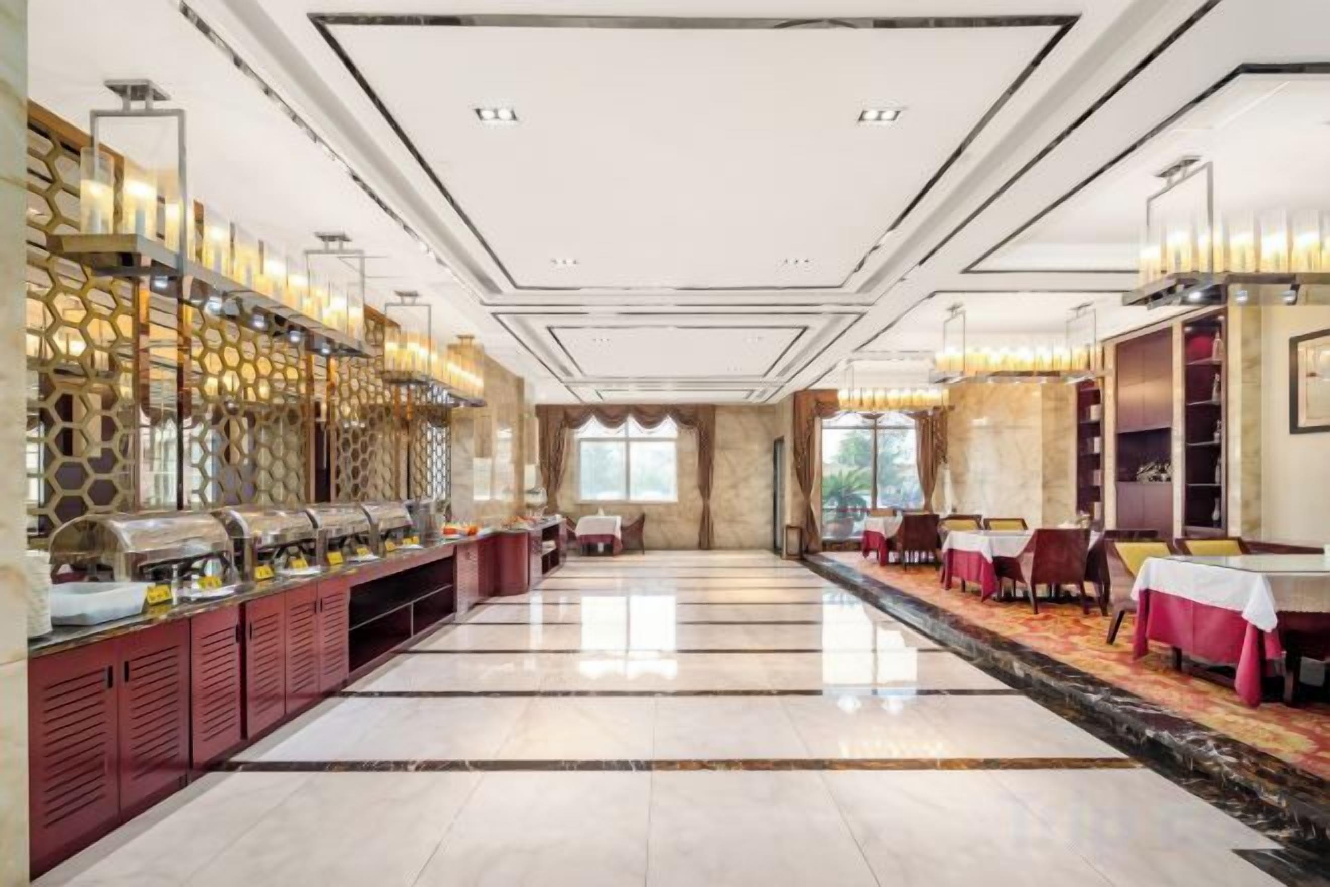 Um amplo hall de hotel com buffet, área de estar e vista através de uma grande janela.