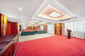 Un salón de conferencias con alfombra roja, un escenario con atril y disposición de asientos.
