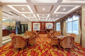 A conference room with a red patterned carpet, wicker chairs, a glass table, and artwork on the walls. - Xinlong Hotel (Wuhan)