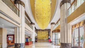 A spacious lobby with high ceilings, large columns, and a prominent chandelier.
