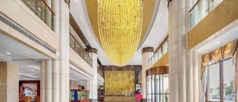 A spacious lobby with high ceilings, large columns, and a prominent chandelier.