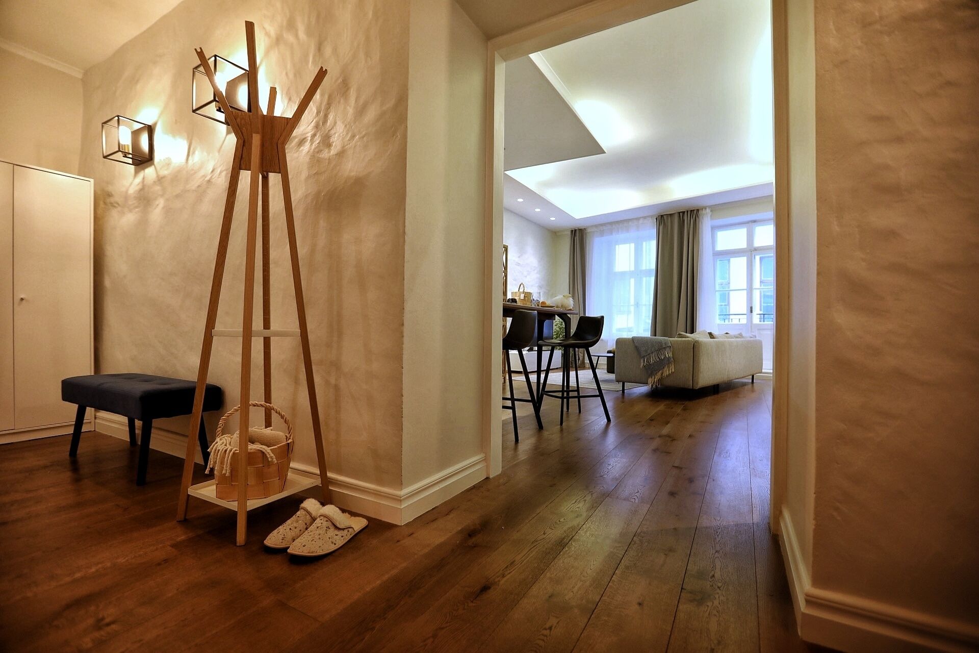 A spacious room with wooden flooring, a black chair, a wooden easel, and a dining area with a table and chairs.