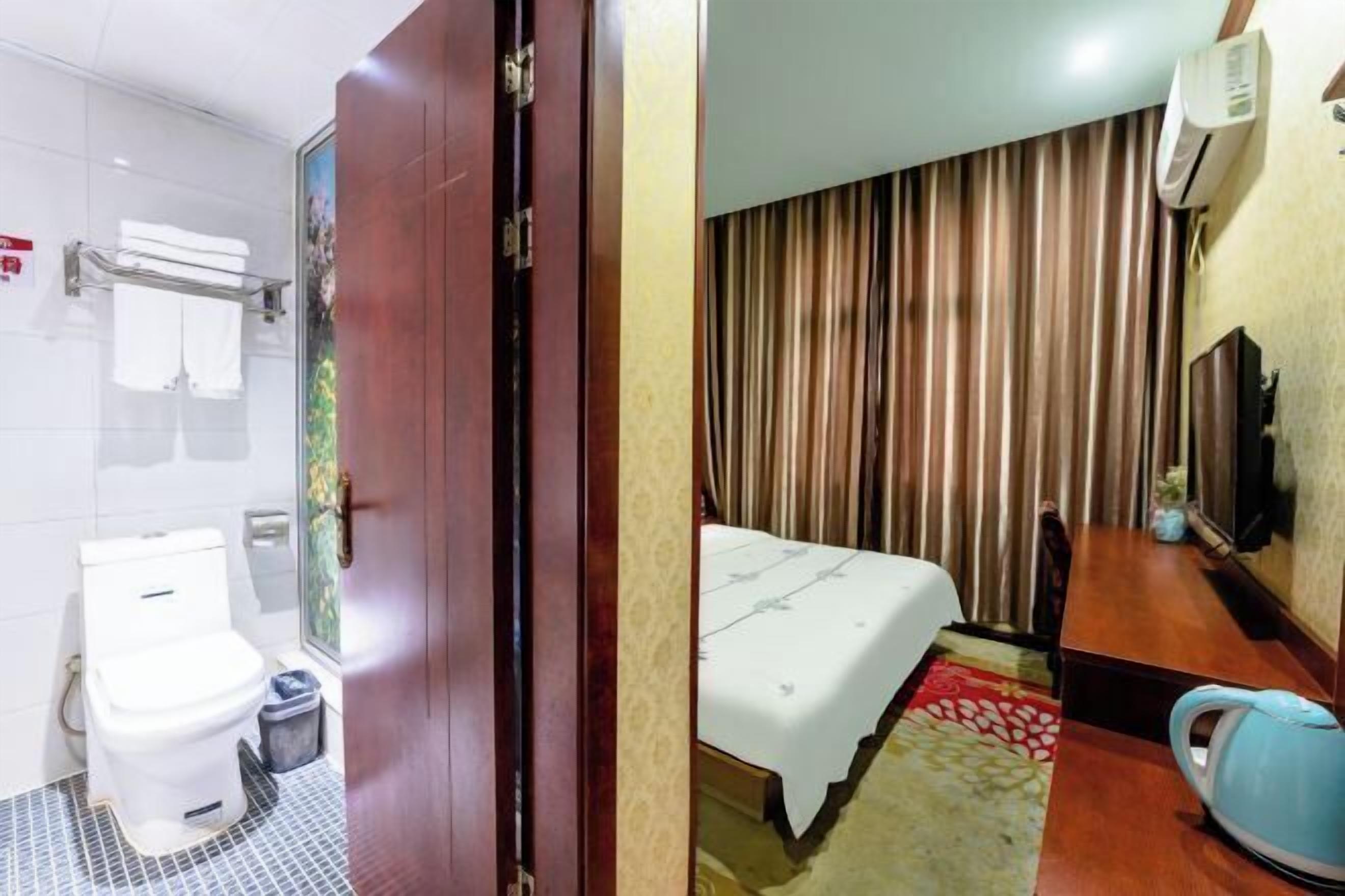 A hotel room with a shower, toilet, bed, and a television.