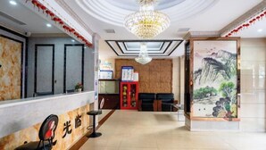 Zona de recepción de un hotel con mostrador de mármol, una araña y un cuadro de un paisaje montañoso.