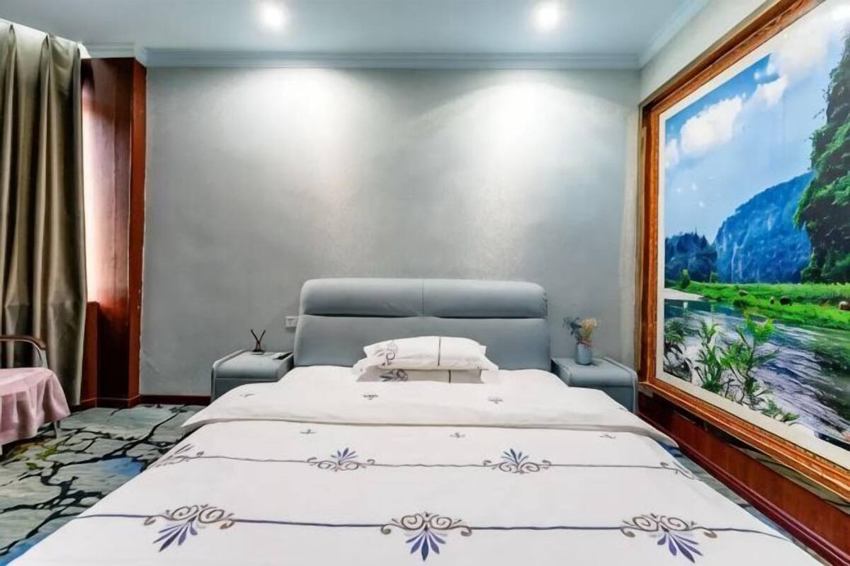 A bedroom with a bed, nightstand, and a painting on the wall.