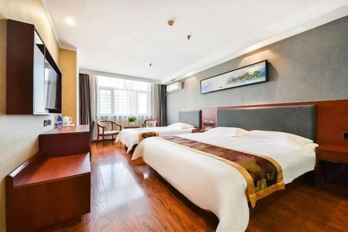 A hotel room with a large bed, a desk, a chair, and a television.