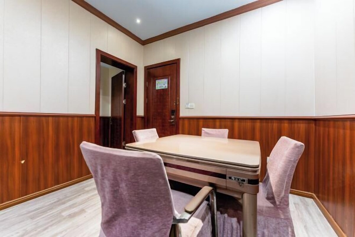 A conference room with a wooden paneled wall, a round table, and four chairs.