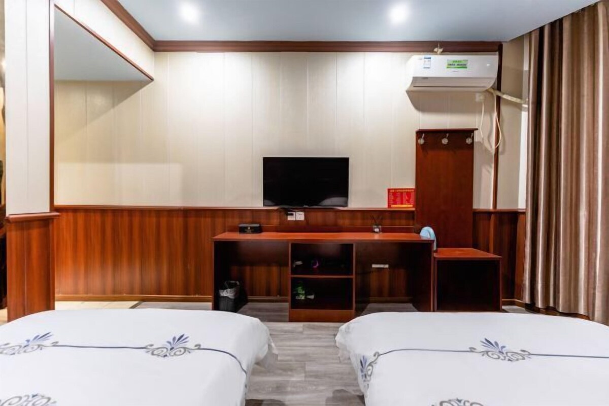 A hotel room with two beds, a desk, a television, and a wardrobe.