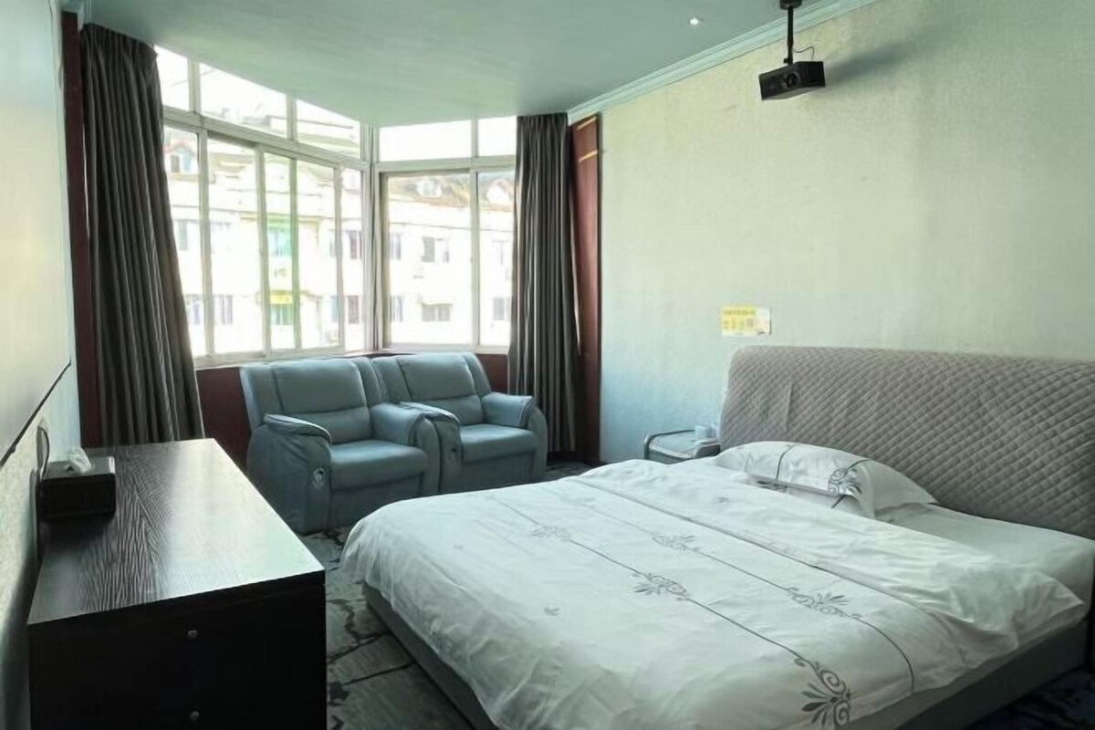 A hotel room with a bed, a desk, a chair, and a window with curtains.