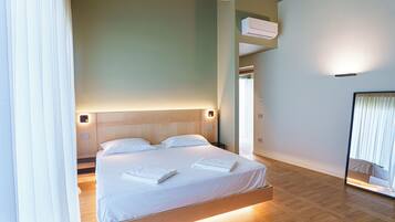Una habitación de hotel moderna con una cama grande, cabecero de madera y un armario empotrado.