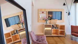 A modern living room with a wooden TV stand, a coffee machine, and a red chair. - Uefio - Luxury Suites (Monte di Procida)