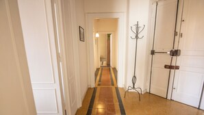 A hallway with a patterned floor, white doors, and a coat rack. - Grazioli Vatican Home (Roma)