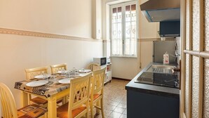 A dining area with a table set for four, a microwave, a stove, and a window with decorative glass. - Grazioli Vatican Home (Roma)