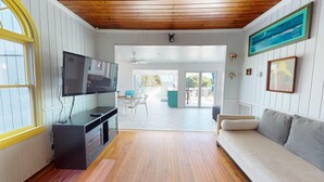 Une pièce avec un plafond en bois, un téléviseur fixé au mur, un canapé et une vue sur l’extérieur.