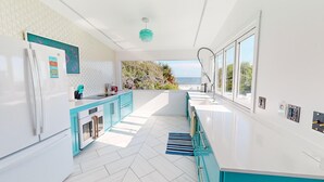 Une cuisine moderne avec vue sur la mer, équipée d’un réfrigérateur, d’un four et d’un évier.