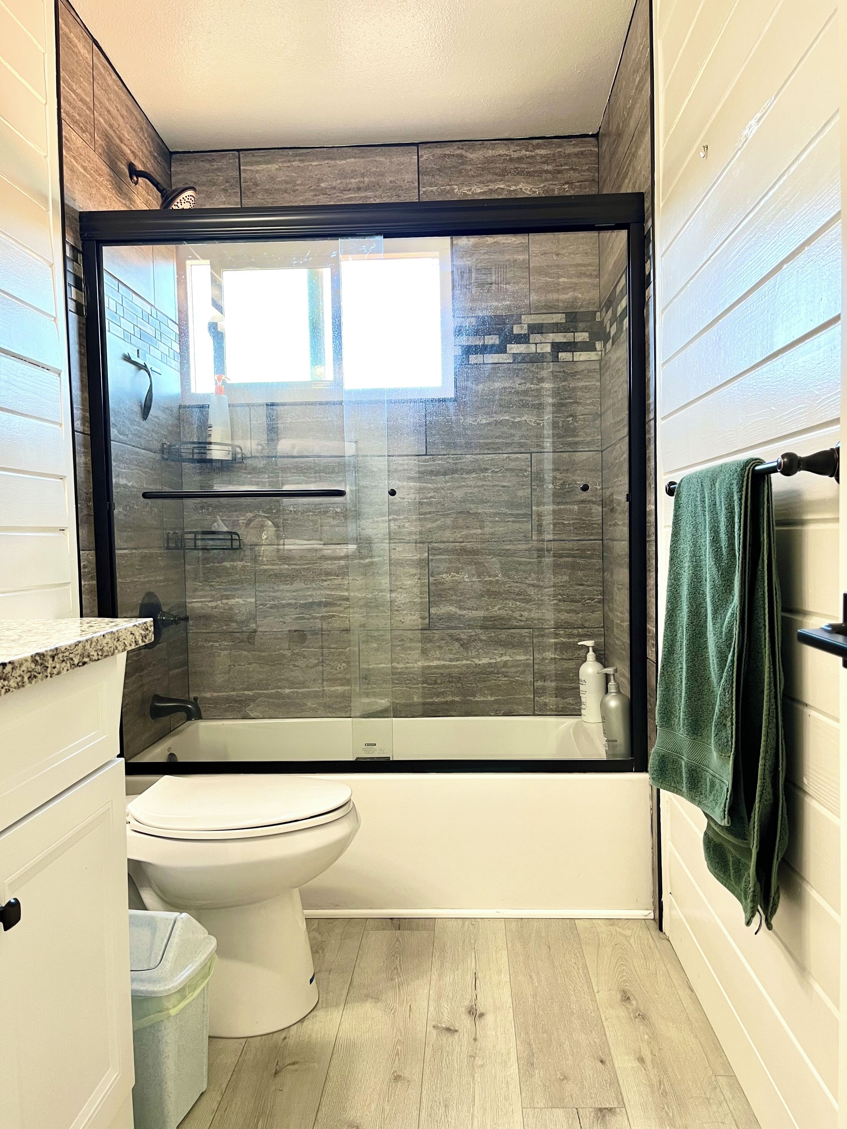 A bathroom with a shower enclosure, toilet, and a towel rack.