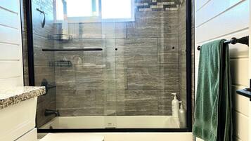 A bathroom with a shower enclosure, toilet, and a towel rack.