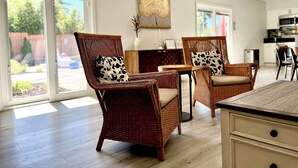 Una sala de estar moderna con muebles de mimbre, una mesa de comedor y una cocina al fondo.
