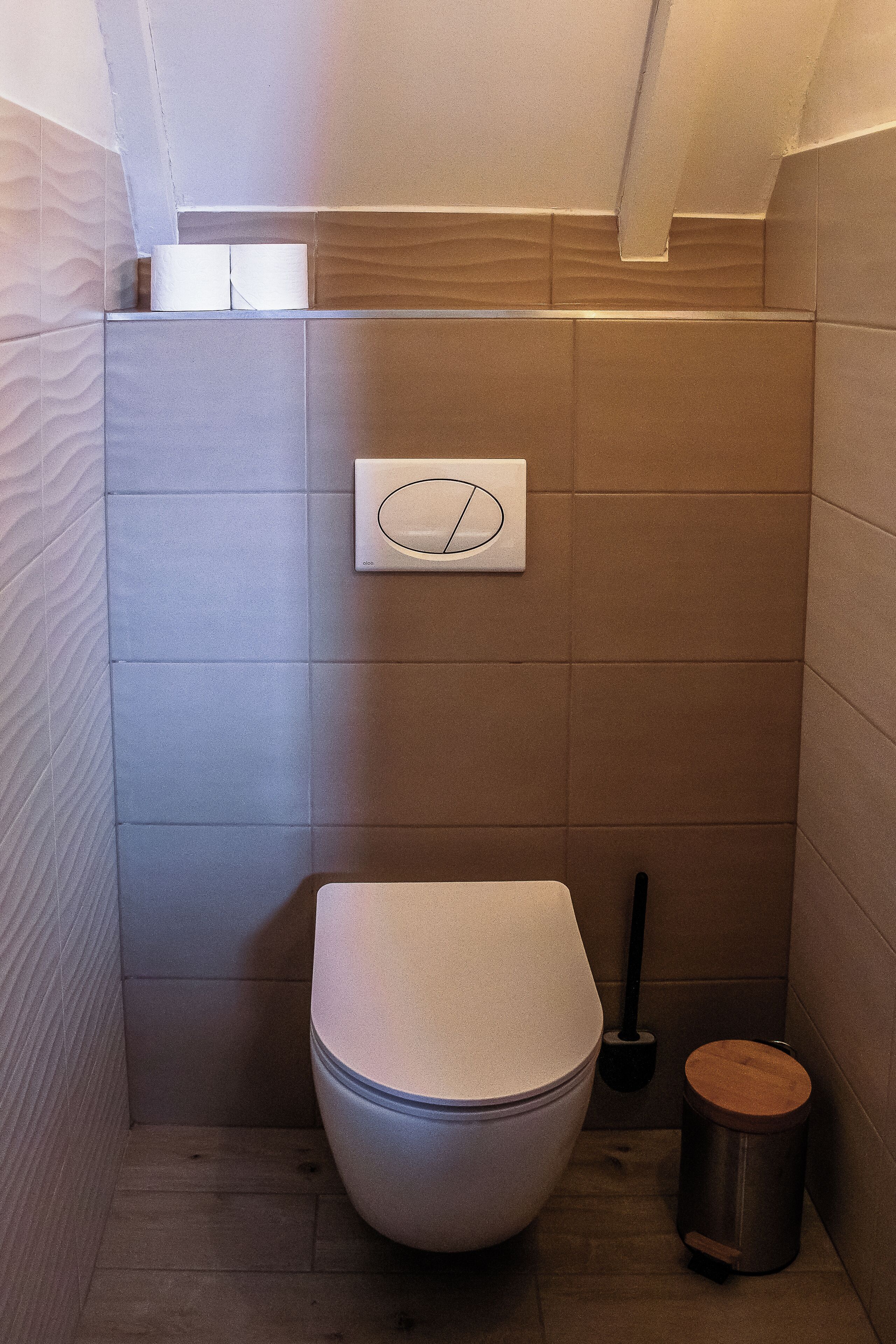 A compact bathroom with a toilet, a bidet, and a trash bin.
