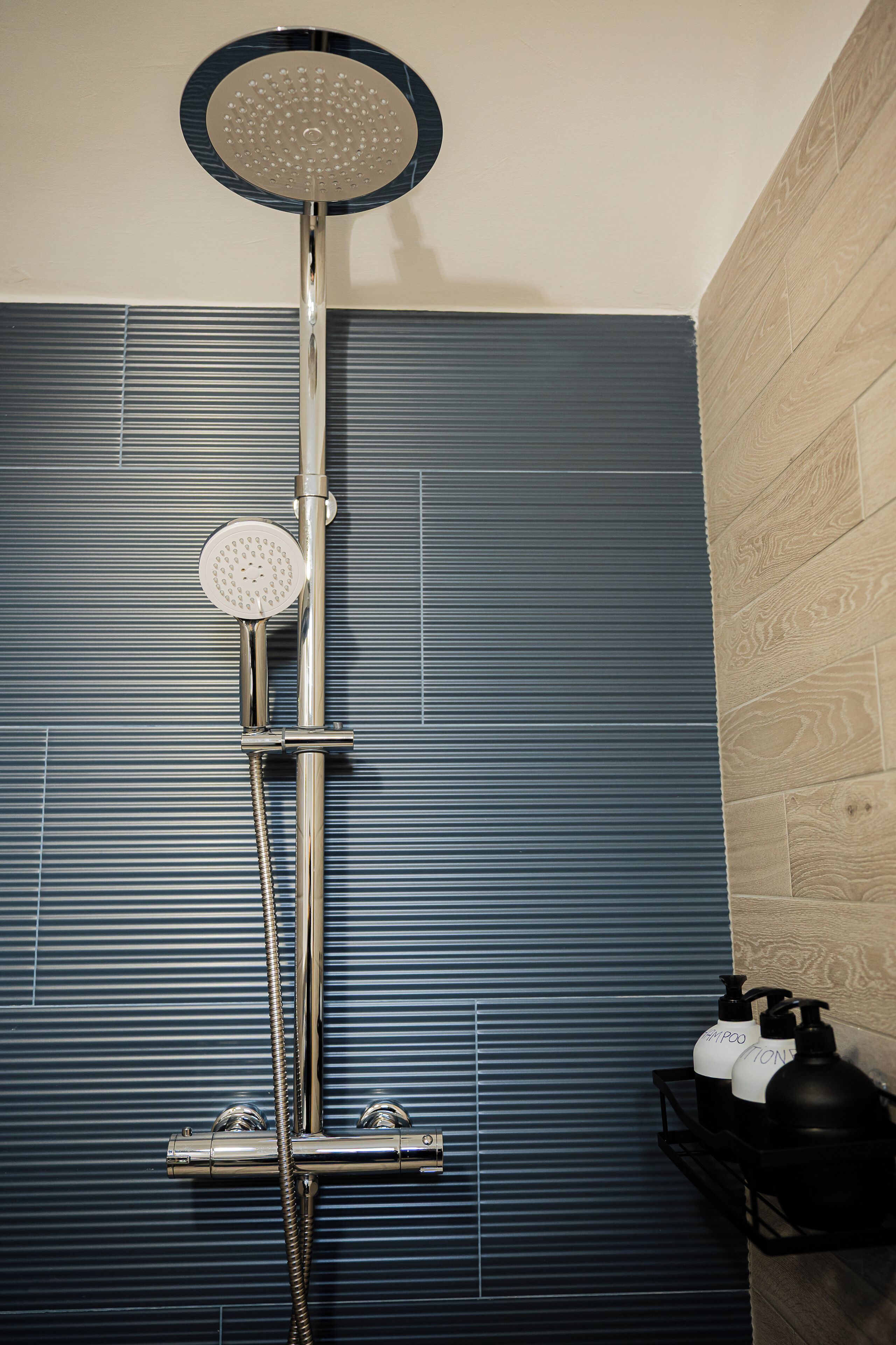 A shower with a handheld showerhead and a wall-mounted control panel.