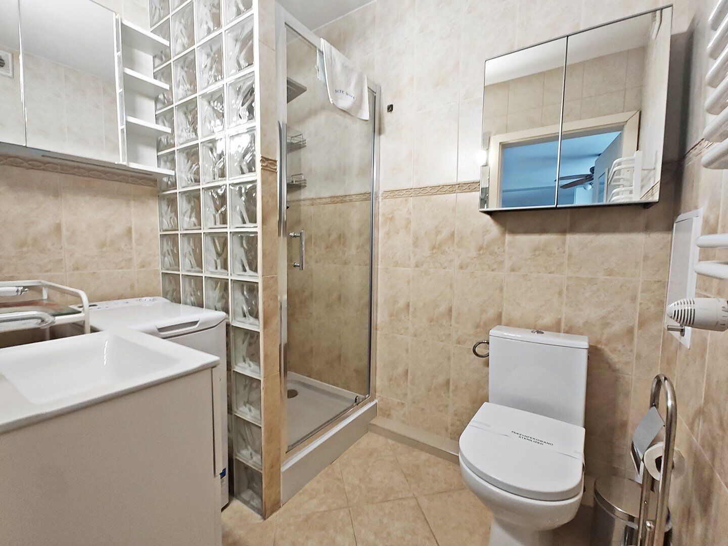 A modern bathroom with a glass shower enclosure, a toilet, and a sink.