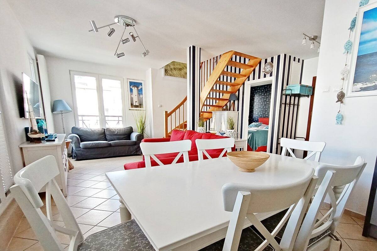 A spacious living area with a dining table, chairs, a sofa, and a staircase.