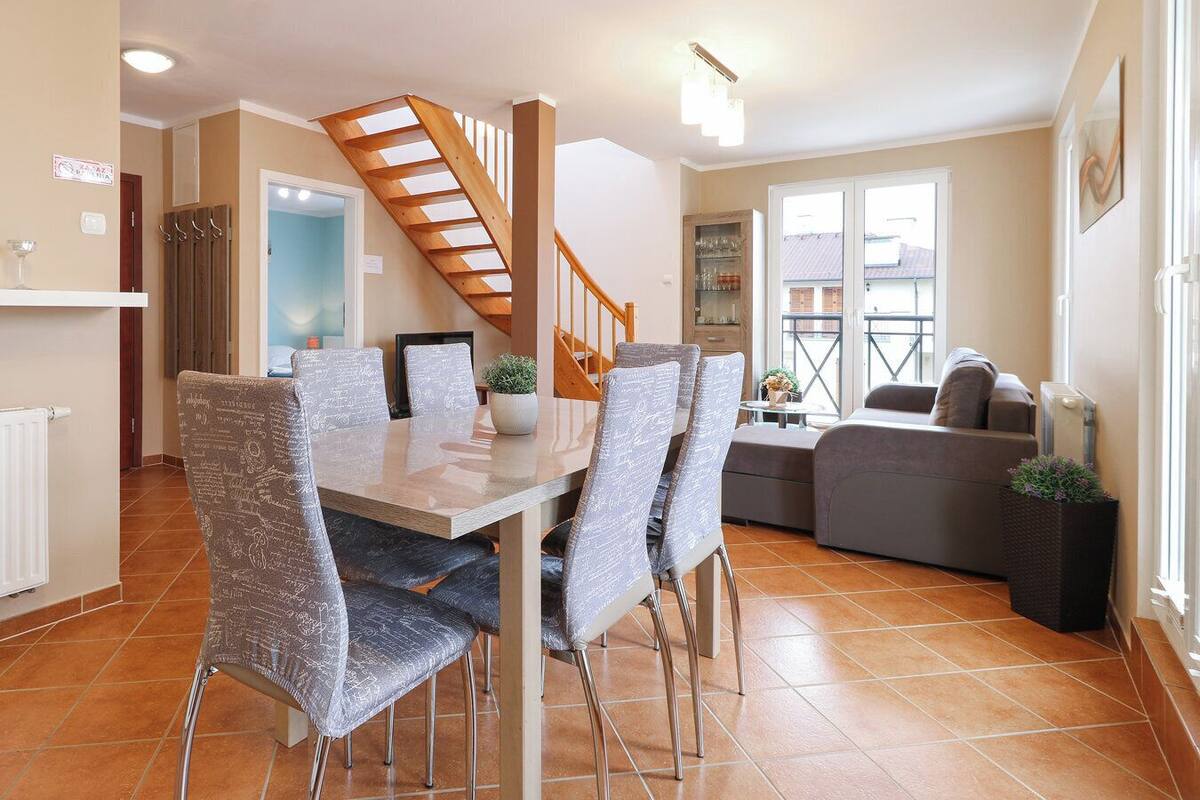 A dining area with a wooden staircase, a sofa, and a small table with a plant.