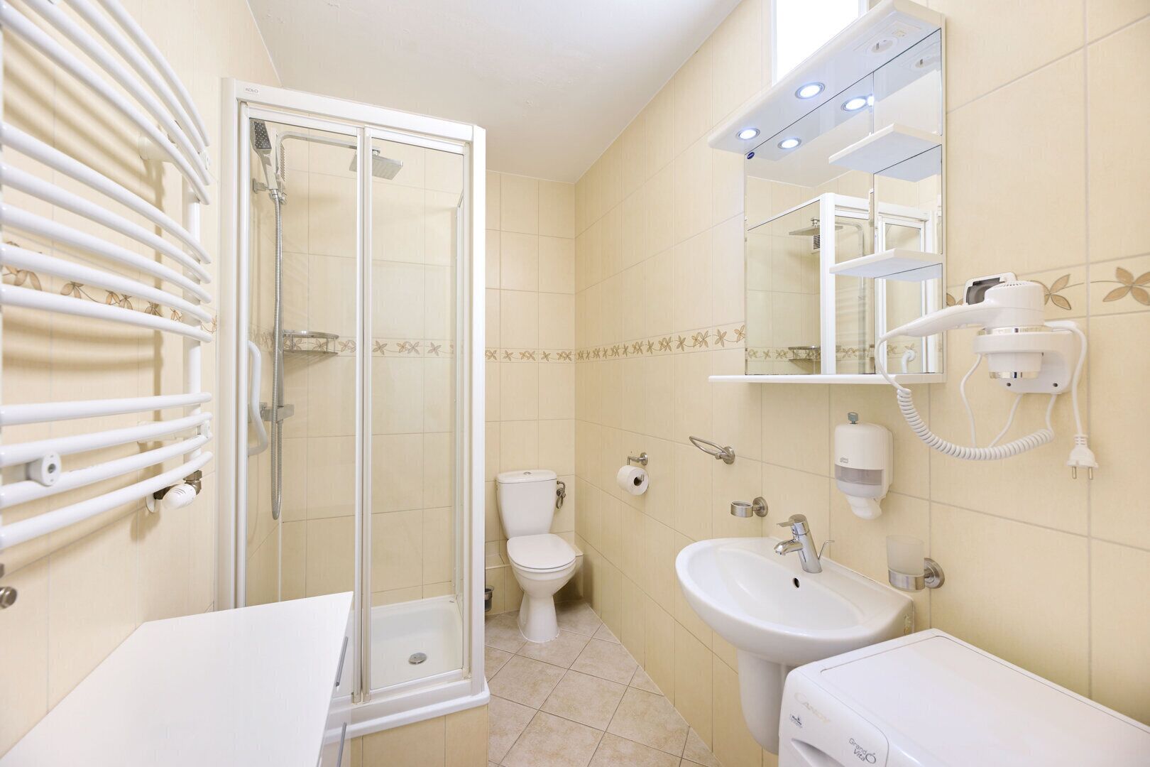 Une salle de bain avec une douche à parois de verre, des toilettes, un lavabo et un meuble-lavabo avec un miroir.
