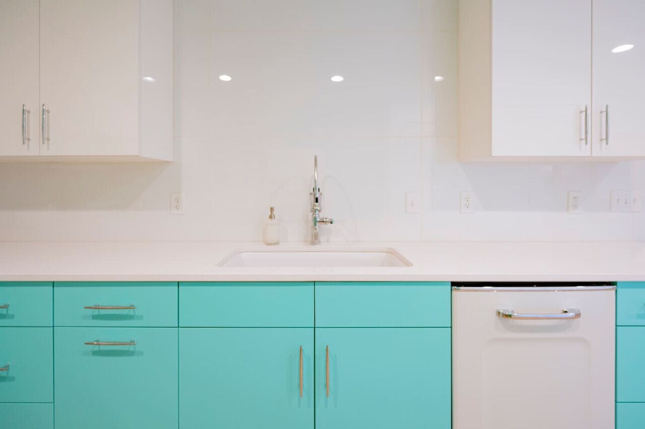 A modern kitchen with white cabinets, a white sink, and a dishwasher.