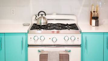 A kitchen with a white stove, teal cabinets, and a white countertop.